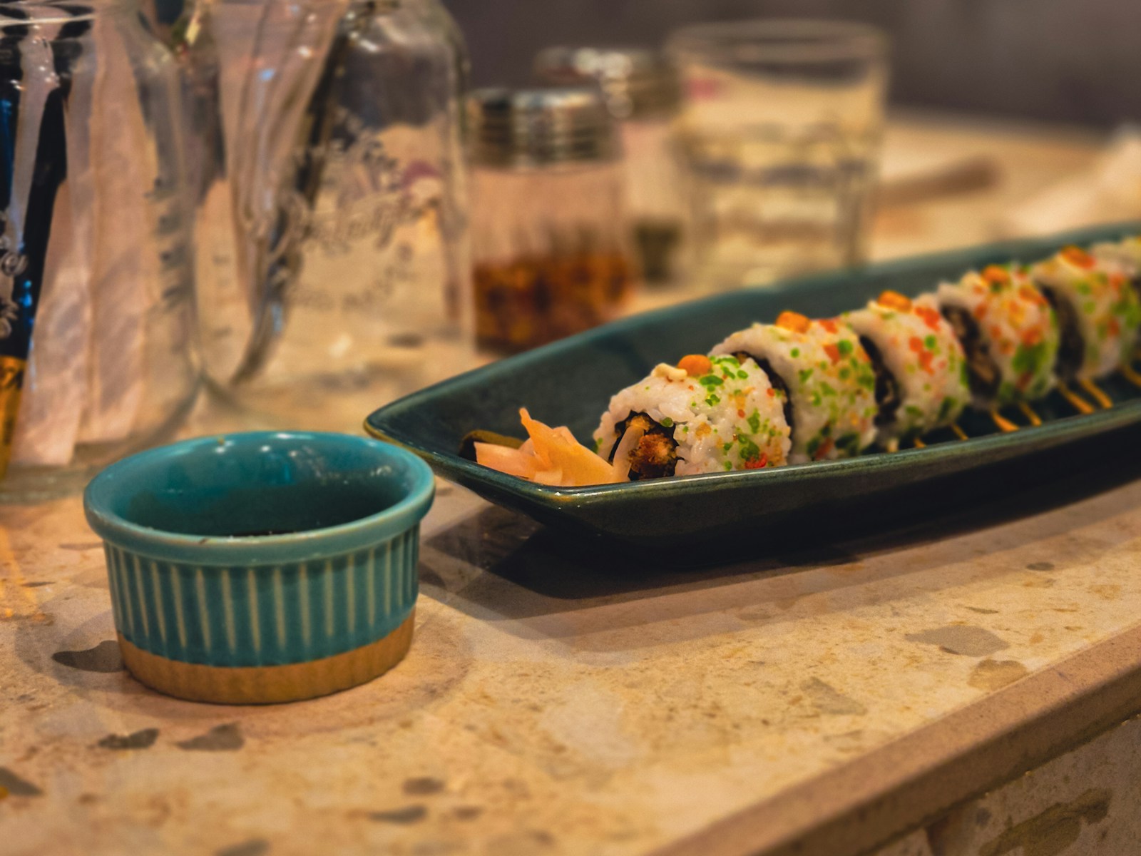 A plate of sushi and a bowl of dipping sauce